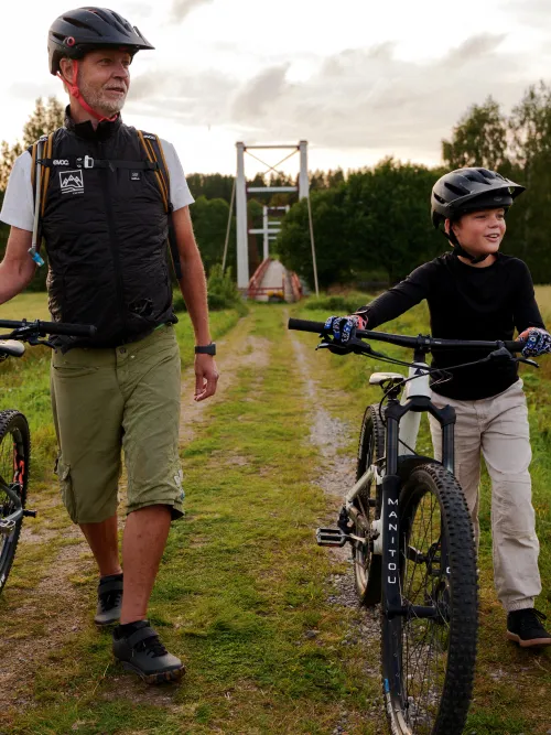 Personer som går med cyklar bort från hängbro i Selet